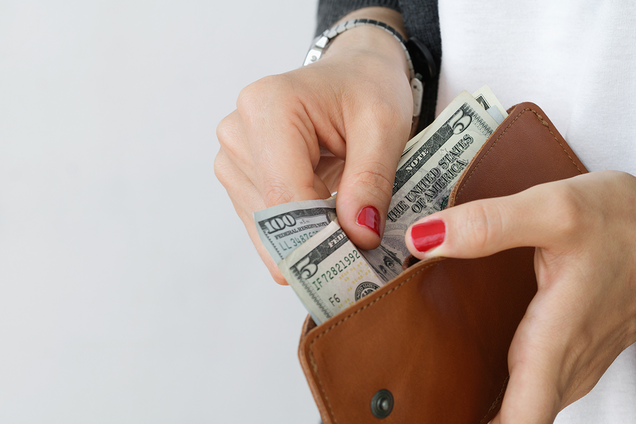 woman putting cash into her wallet